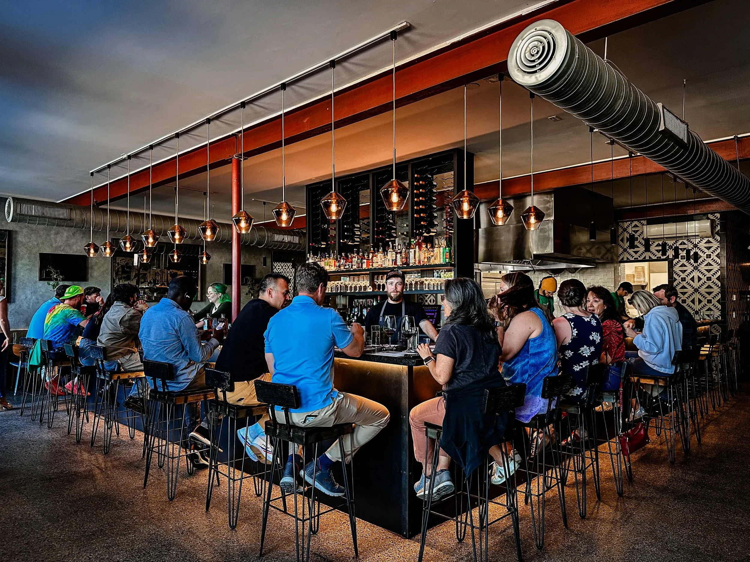 Guests seated around the bar under copper pendant lights