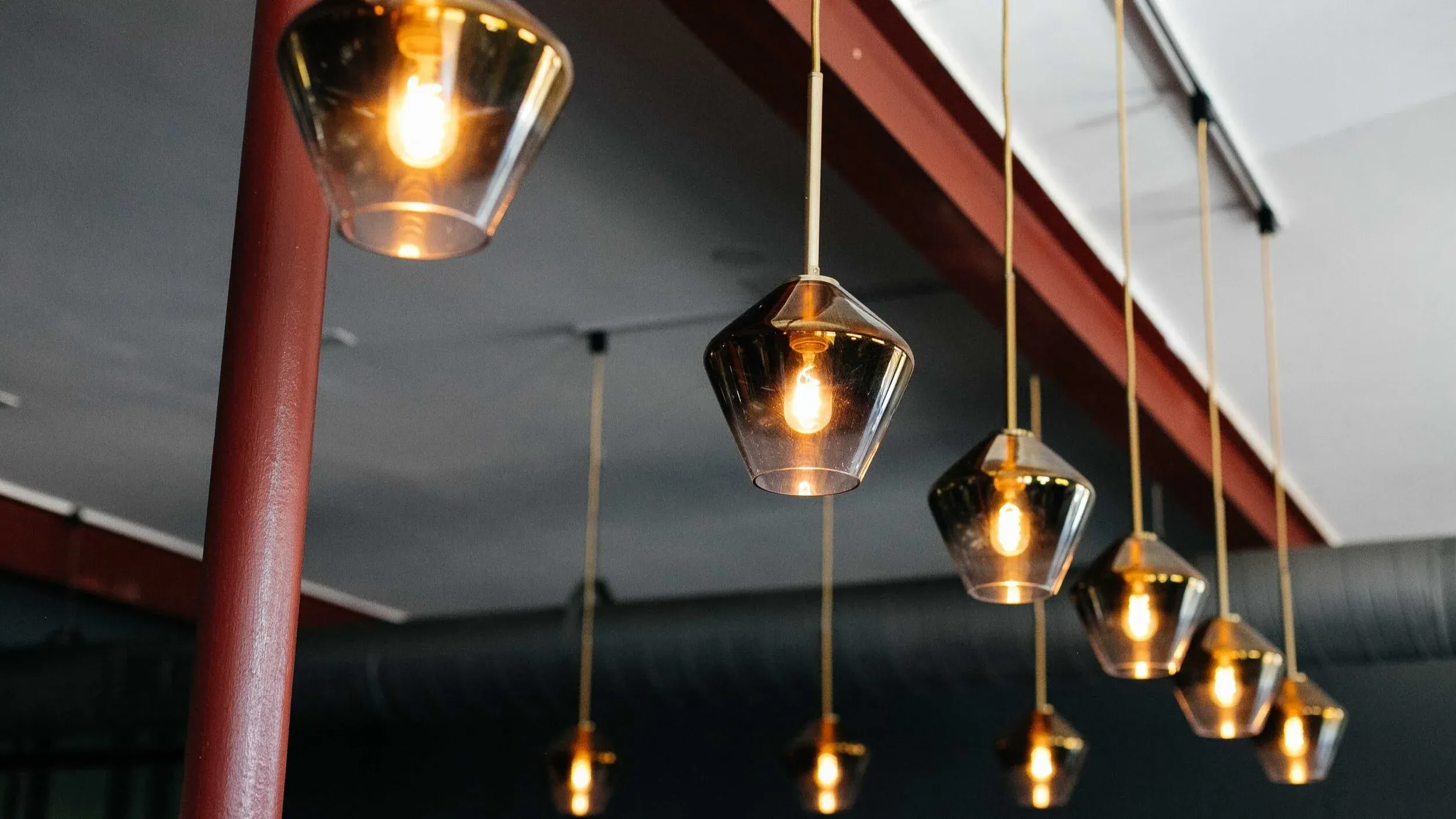 Smoked glass pendant lights hanging from the red beams of the dining room